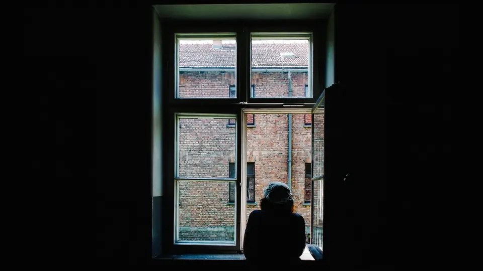 Fake-Profile erkennen beim Online-Dating: eine Silhouette am dunklen Fenster