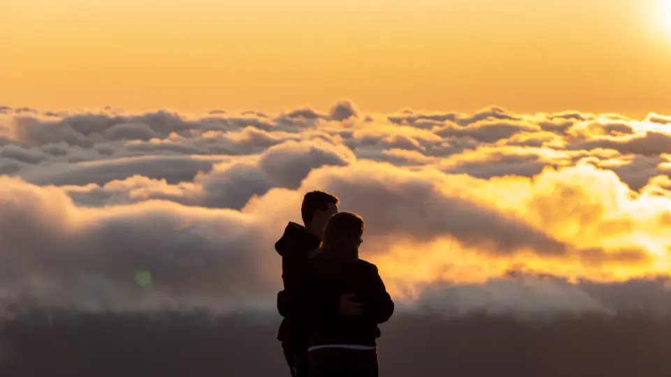 Sex Dating Wien: ein Paar umarmt sich über einem Wolkenmeer bei Sonnenuntergang